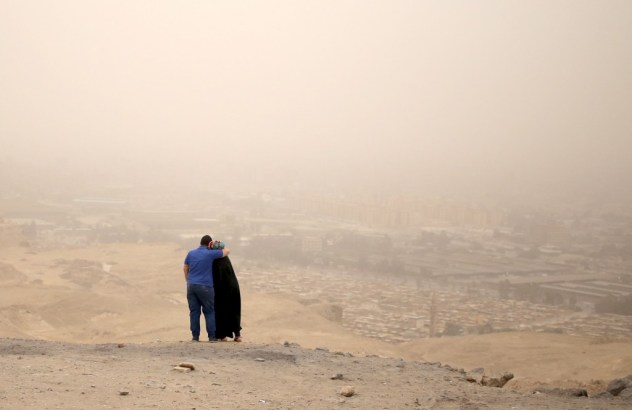 A couple hugs while standing on a hilly area overlooking Cairo on a dusty and hazy day where temperatures reached 114 Fahrenheit, May 27, 2015. REUTERS/Asmaa Waguih